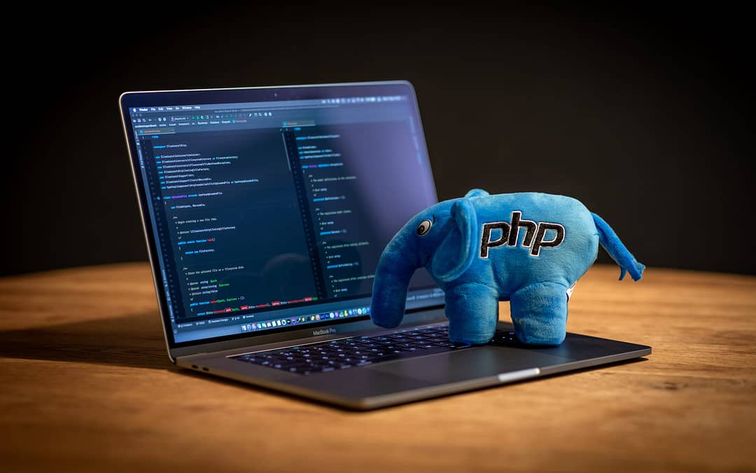 Macbook Pro on a desk with a stuffed blue php elephant, dark background